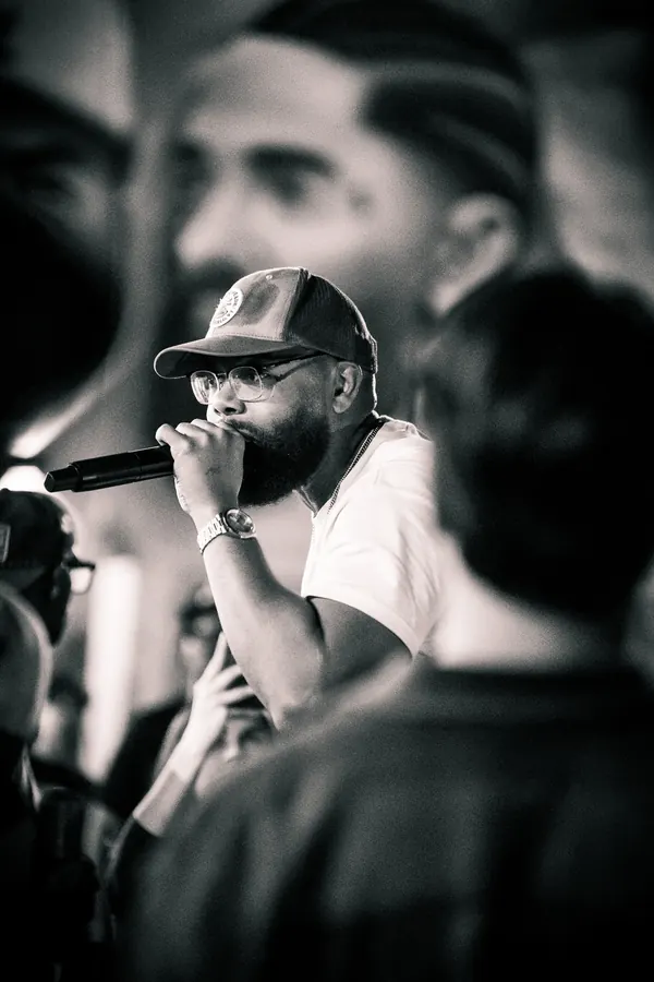 Black-and-white photo of a performer rapping into a microphone in a crowd