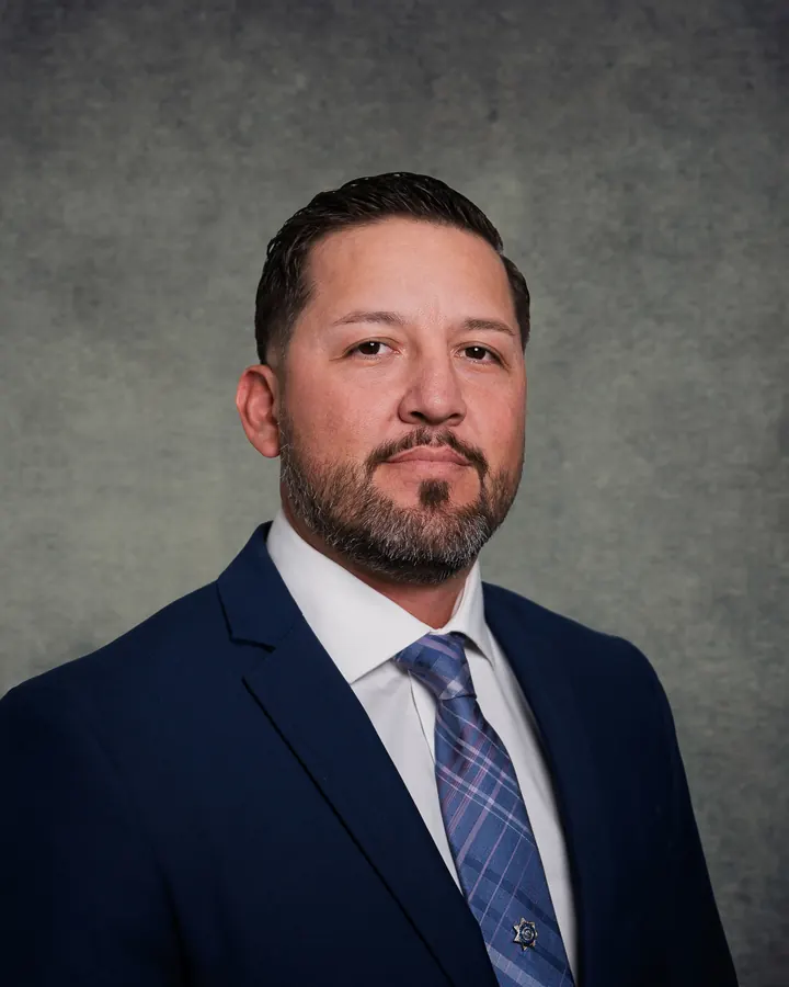 Executive headshot of a man in a navy suit against a textured studio backdrop