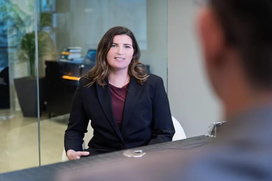 Professional woman seated at a conference table in a glass-walled office