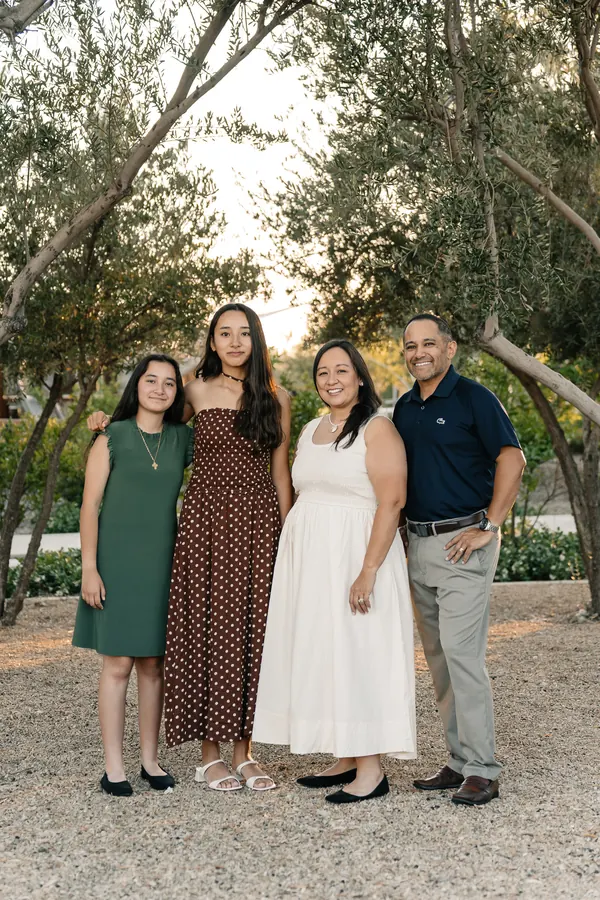 Family of four standing together among olive trees