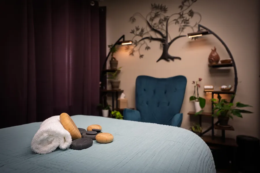 Softly lit massage room with hot stones and a rolled towel on the table